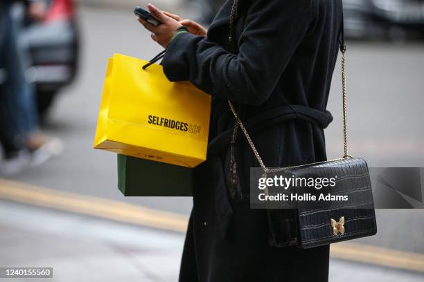 Shopper carries a shopping bag outside Harrods luxury department store on April 22, 2022 in London, England. The country's Office of National...