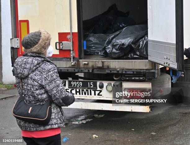 Tania Boikiv looks at a refrigerated lorry with exhumed bodies at a morgue in Bucha, northwestern of Kyiv, on April 22, 2022. - "Today I came here,...