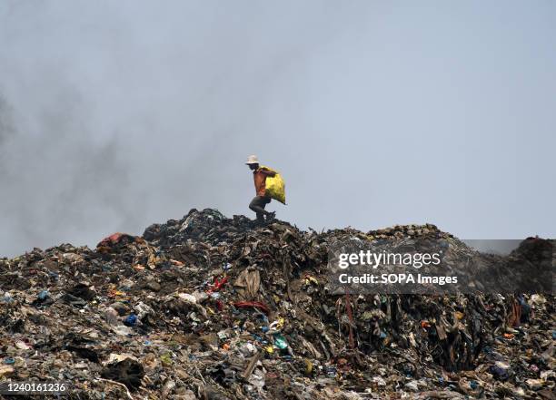 Man walks on a heap of garbage at a dumping ground during Earth Day on the outskirts of Mumbai. Earth Day is celebrated annually on 22nd April to...