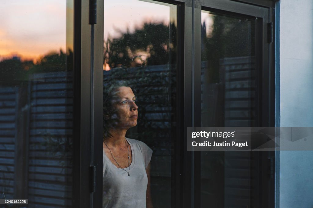 Woman looking through window at dusk