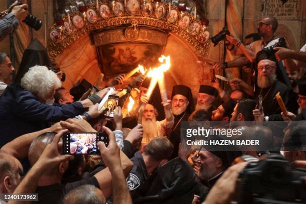 Greek Orthodox Patriarch of Jerusalem Theophilos III holds candles as Christians gather around the Edicule, traditionally believed to be the burial...