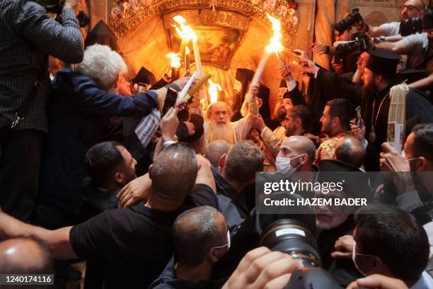 Greek Orthodox Patriarch of Jerusalem Theophilos III holds candles as Christians gather around the Edicule, traditionally believed to be the burial...