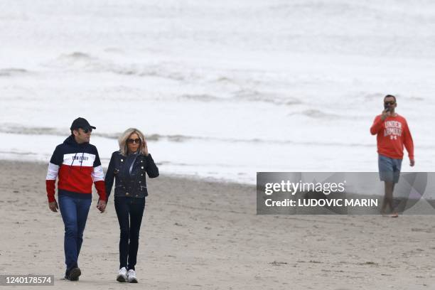 French President and La Republique en Marche party candidate for re-election Emmanuel Macron and his wife Brigitte Macron walk along the beach in Le...
