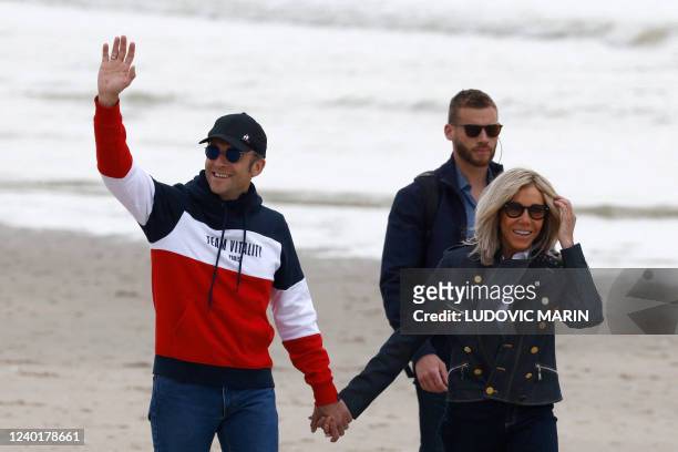 French President and La Republique en Marche party candidate for re-election Emmanuel Macron waves as he walks along the beach with his wife Brigitte...