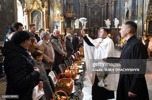 Worshippers attend a service marking Orthodox Easter at Saints Peter and Paul Garrison Church, in Lviv, western Ukraine, on April 23, 2022. -...