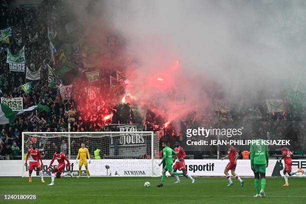Saint-Etienne's French Algerian midfielder Ryad Boudebouz runs with the ball as ASSE's supporters light flares during the French L1 football match...