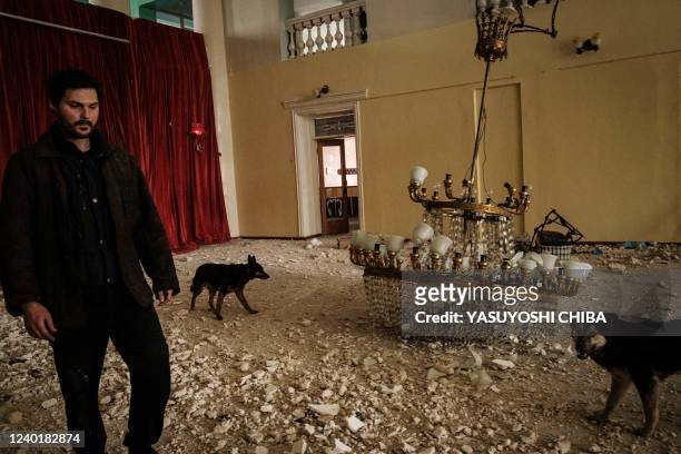 An internally displaced man walks with dogs in the destroyed building of the Palace of culture by shelling in Rubizhne, eastern Ukraine, on April 23,...