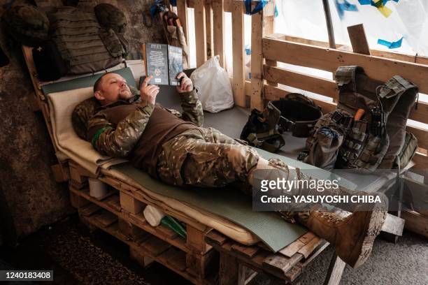 Ukrainian soldier reads a book as he rests at a checkpoint in Bakhmut, eastern Ukraine, on April 23, 2022 amid the Russian invasion of Ukraine.