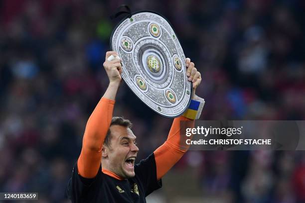 Bayern Munich's German goalkeeper Manuel Neuer raises a mock-up Bundesliga trophy after the German first division Bundesliga football match FC Bayern...