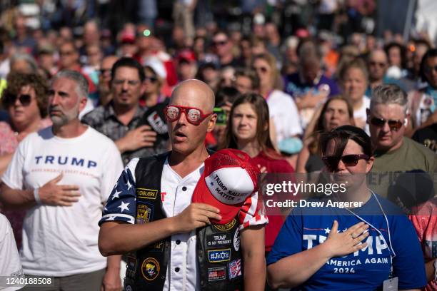 The crowd stands for the Pledge of Allegiance during a rally hosted by former President Donald Trump at the Delaware County Fairgrounds on April 23,...