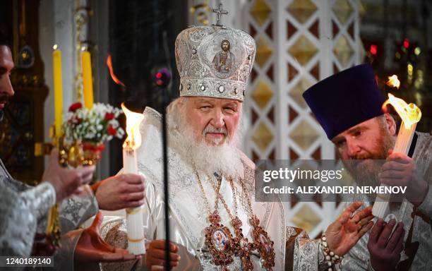 Russian Orthodox Patriarch Kirill holds candles representing the Holly Light with during an Orthodox Easter service, late on April 23, 2022 in Moscow.