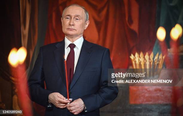 Russian President Vladimir Putin holds a candle during an Orthodox Easter service, late on April 23, 2022 in Moscow.