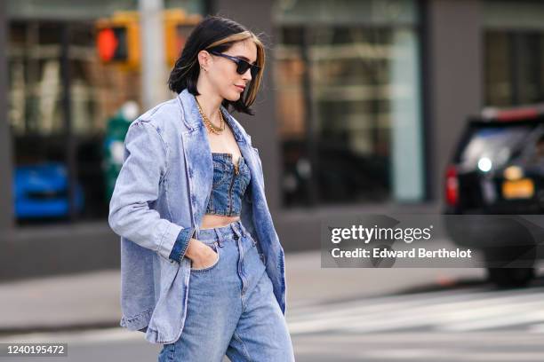 Brittany Xavier wears sunglasses, a blue denim jacket, blue denim bras, blue jeans, a necklace, outside Self Portrait, during New York Fashion Week...