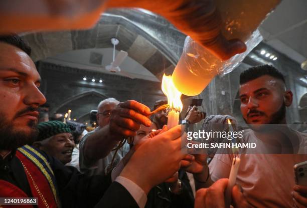 Iraqi Orthodox Christians celebrating Easter Saturday share the flame of the Holy Fire brought from Jerusalem, at the church of the ancient Mar Matta...
