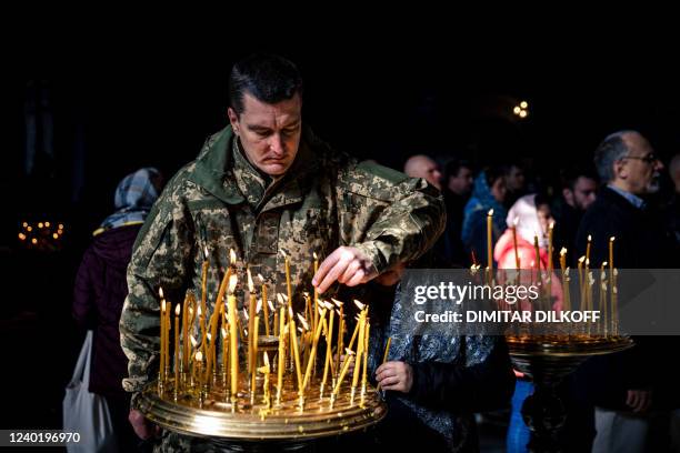 Ukrainian soldier lights a candle during an Orthodox Easter service in St. Volodymyr's Cathedral in Kyiv on April 24 two months after the start of...