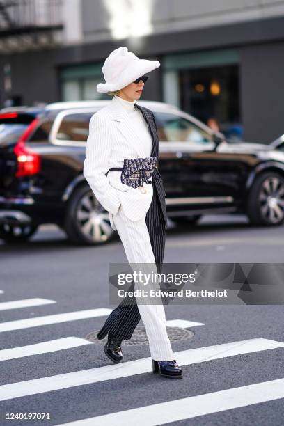 Guest wears a white fluffy hat, a black and white checked jacket, a white turtleneck pullover, a Dior Saddle belt bag, bi-color black and white...