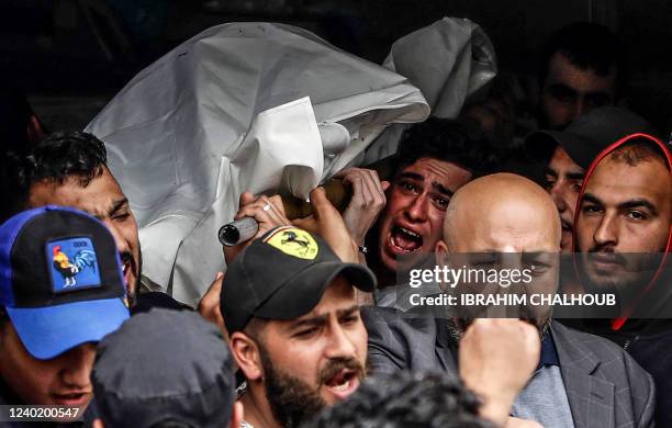 Mourners carry the body of one of the people who died when their boat capsized a day earlier off the coast of Tripoli, at the morgue of a hospital of...