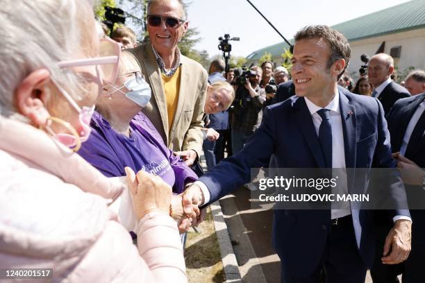 French President and liberal party La Republique en Marche candidate for re-election Emmanuel Macron shakes hands with wellwishers after voting for...