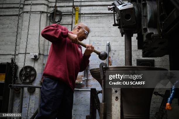 Bell tuner Girdar Vadukar tests the sound as he works to remove layers of metal from the interior of a 300 year old bell to retune it, in the John...