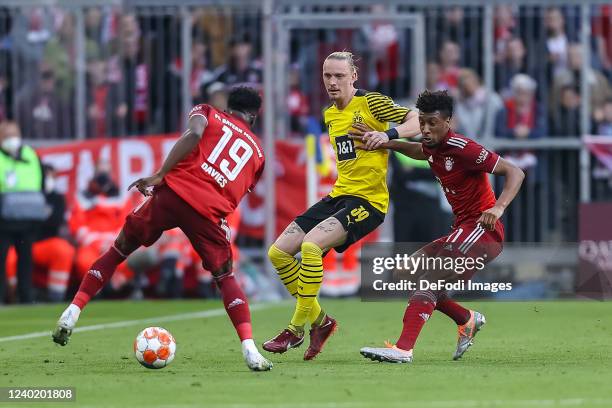 Alphonso Davies of Bayern Muenchen, Marius Wolf of Borussia Dortmund and Kingsley Coman of Bayern Muenchen battle for the ball during the Bundesliga...