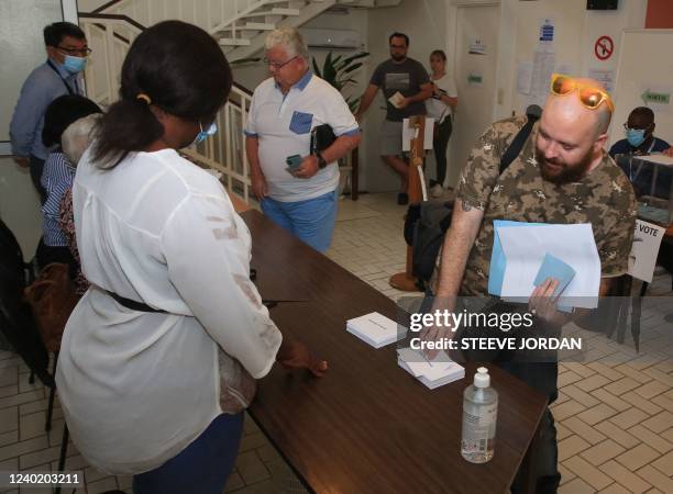 Man picks up a ballot to vote in France's second round of Presidential elections at a voting station at the French consulate in downtown Libreville,...