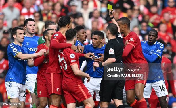 Referee Stuart Attwell shows a yellow card to Everton's French midfielder Abdoulaye Doucoure and Liverpool's Senegalese striker Sadio Mane during the...