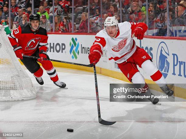 Adam Erne of the Detroit Red Wings reaches for the puck as he skates against Ryan Graves of the New Jersey Devils during the second period at the...