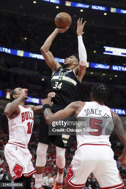 Bucks forward Giannis Antetokounmpo shoots over Bulls forward DeMar DeRozan as Derrick Jones Jr. Looks on in the first half at the United Center on...