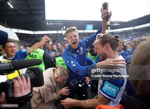 Korbinian Burger of Magdeburg gets showered in beer by goalkeeper Benjamin Leneis of Magdeburg as they celebrate promotion to the Second Bundesliga...