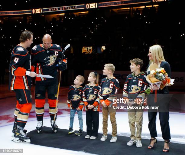Cam Fowler of the Anaheim Ducks gives Ryan Getzlaf a retirement present during his retirement ceremony prior to his last career NHL game before the...