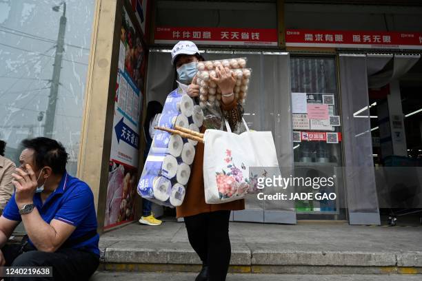 Woman leaves a supermarket after buying food and household provisions in Beijing on April 25, 2022. - Fears of a hard Covid lockdown sparked panic...