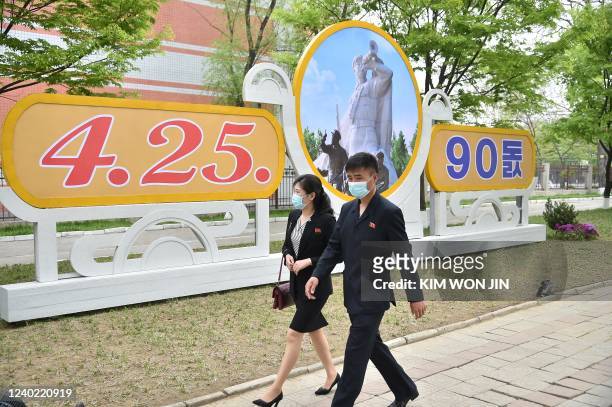 People walk past a display marking the 90th founding anniversary of the Korean People's Revolutionary Army in Pyongyang on April 25, 2022.