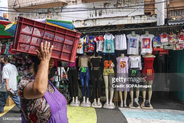 Woman walks by a clothing shop at a local market in downtown San Salvador. On April 21, the Salvadoran Ministry of Health announced they would lift...