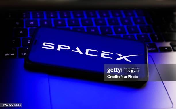 SpaceX logo displayed on a phone screen and a laptop keyboard are seen in this illustration photo taken in Poland on April 24, 2022.