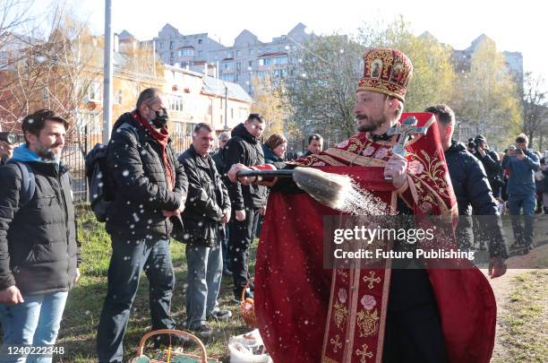 Priest blesses people and their baskets with holy water outside the Church of Saint Andrew the First-Called Apostle during the Orthodox Easter...