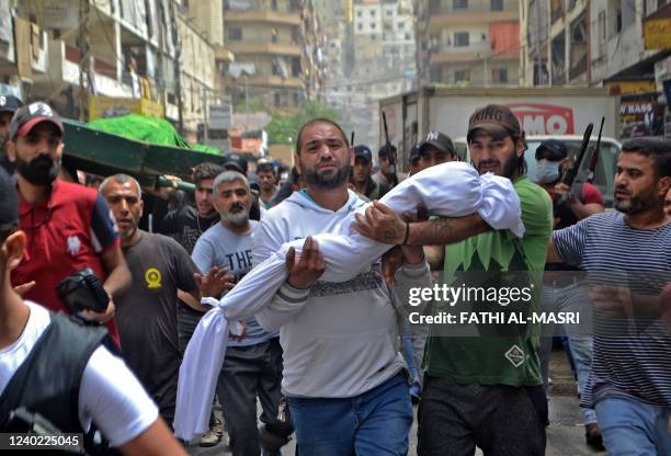 Mourners carry the body of a child, killed after a boat loaded with migrants capsized near the coast of the northern city of Tripoli, during a...