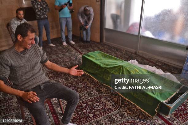 Mourners sit next to a body, killed after a boat loaded with migrants capsized near the coast of the northern city of Tripoli, during a funeral in...