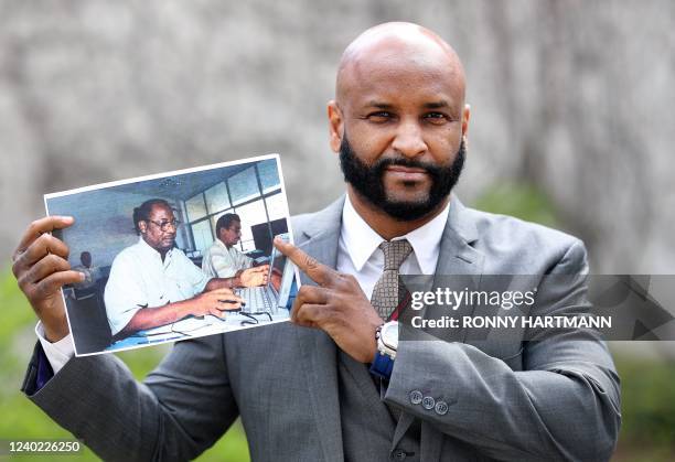 Baba Hydara, son of the late Deyda Hydara, poses with a photo of his father on the sidelines of the trial against Gambian defendant Bai L., accused...