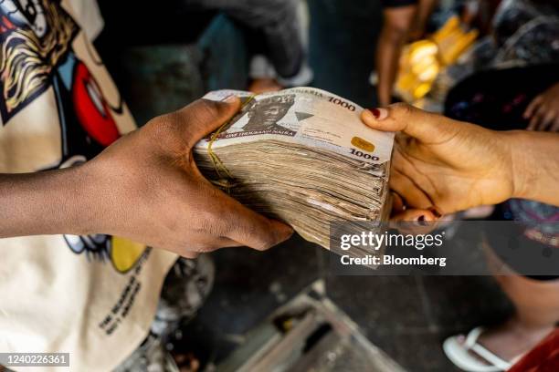Customer hands over bundles of 1000 Naira banknotes to a trader inside a market in Lagos, Nigeria, on Friday, April 22, 2022. Choked supply chains,...