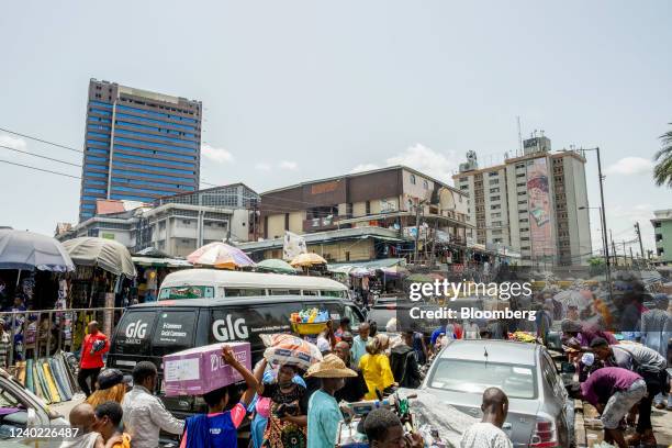 Informal traders and pedestrians move between heavy traffic in a market area of Lagos, Nigeria, on Friday, April 22, 2022. Choked supply chains,...