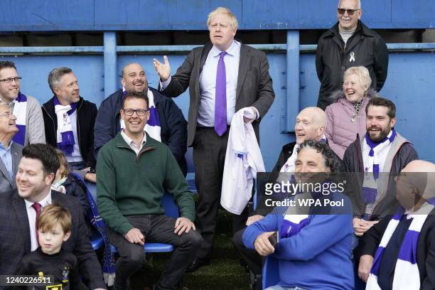 Prime Minister Boris Johnson gestures as among fans in the stands during a visit to Bury FC at their Gigg Lane ground, on April 25, 2002 in Bury,...