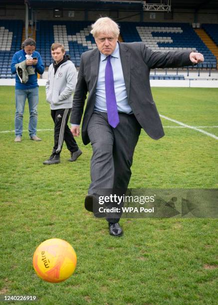 Prime Minister Boris Johnson kicks a football during a visit to Bury FC at their Gigg Lane ground, on April 25, 2002 in Bury, Greater Manchester,...