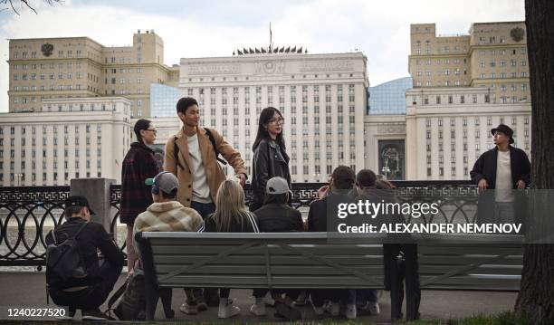 People spend time at an embankment of the Moskva river, with the Russian Defence Ministry headquarters seen in the background, in Moscow on April 25,...