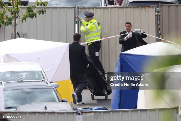 Body bag and gurney from a private ambulance is taken to the scene where three women and a man were found stabbed to death on April 25, 2022 in the...