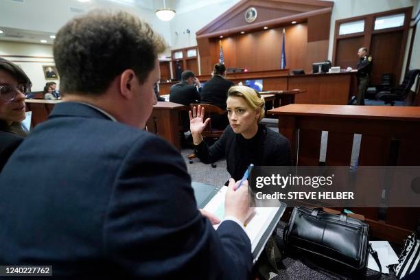 Actor Amber Heard talks to her attorneys before the hearing starts in the courtroom at the Fairfax County Circuit Courthouse in Fairfax, Virginia,...