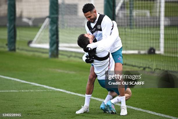 Manchester City's Algerian midfielder Riyad Mahrez gugs and jikes with Manchester City's Portuguese midfielder Bernardo Silva as they take part in a...