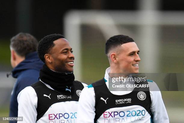 Manchester City's English midfielder Raheem Sterling and Manchester City's English midfielder Phil Foden react as they take part in a training...