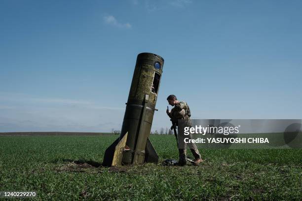 Ukrainian serviceman looks at a Russian ballistic missile's booster stage that fell in a field in Bohodarove, eastern Ukraine, on April 25 amid the...