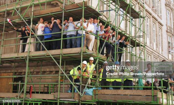 Building workers and office staff watch from scaffolding as the England cricket team's Ashes victory bus parade passes Savoy Court on the Strand on...