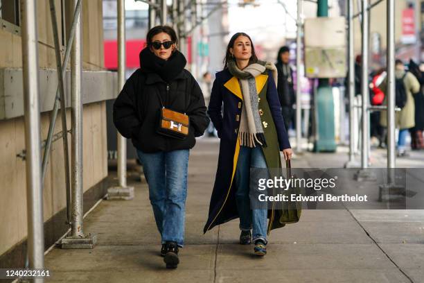 Sylvia Haghjoo wears sunglasses, a large scarf, a black oversized puffer jacket, a brown Hermes bag, blue jeans ; Julia Haghjoo wears a wool fringed...